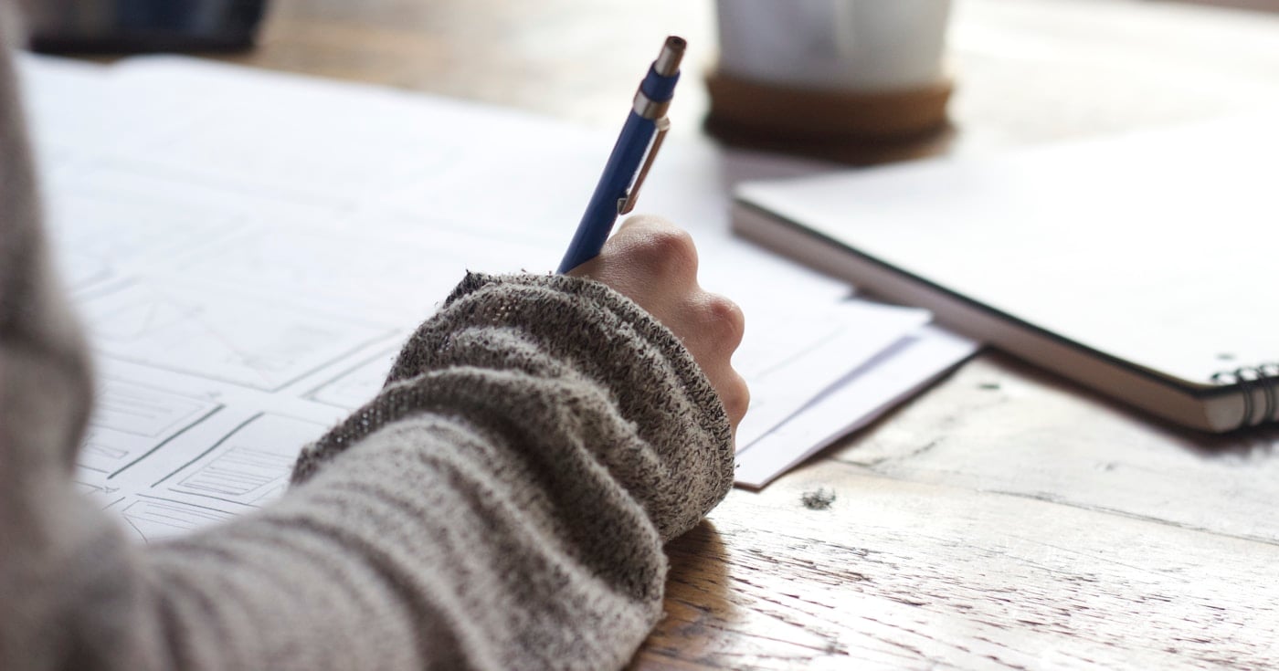Designer sketching a web design proposal on paper