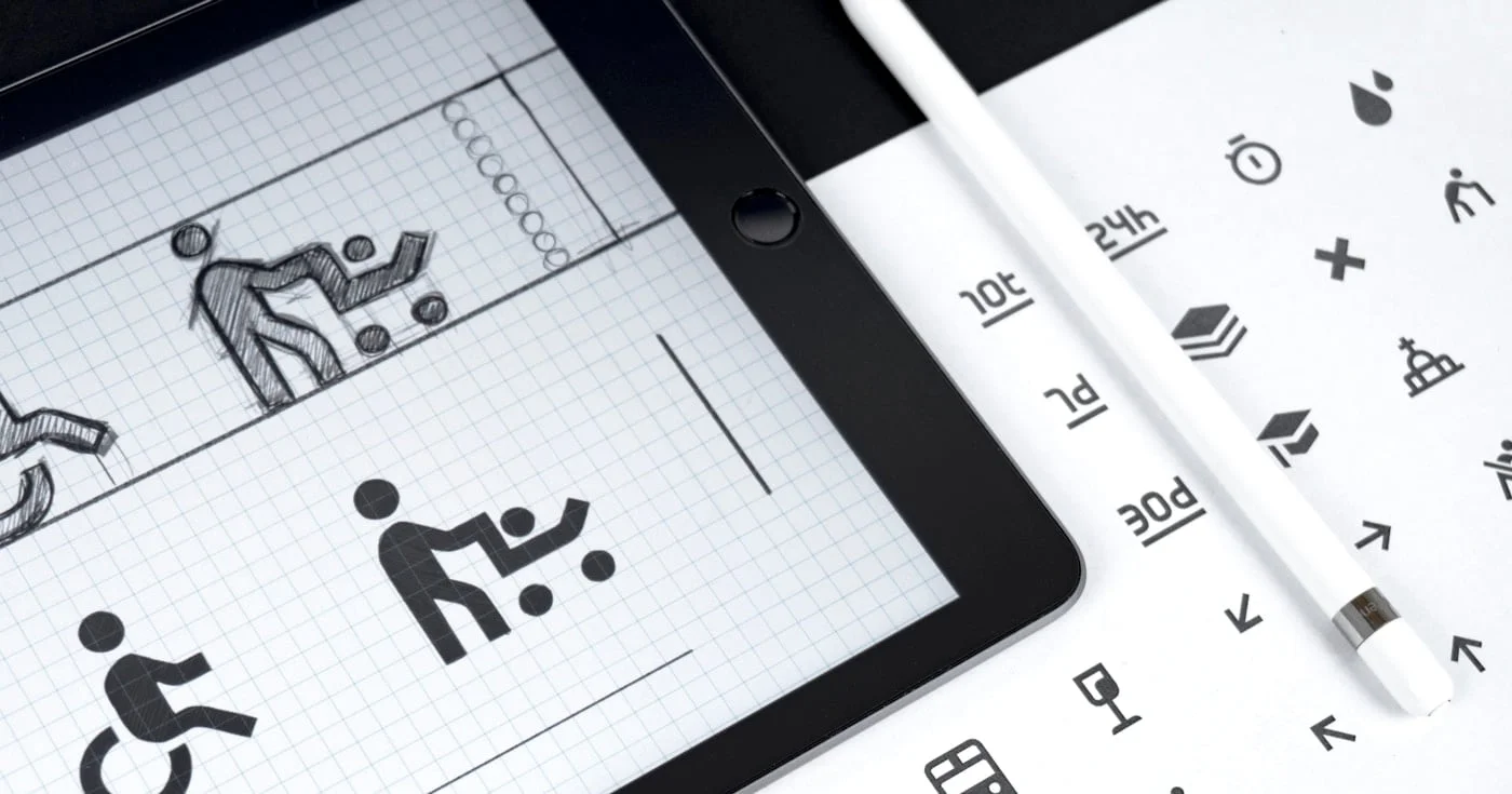 Tablet showing accessibility icon sketches next to a printed icon set